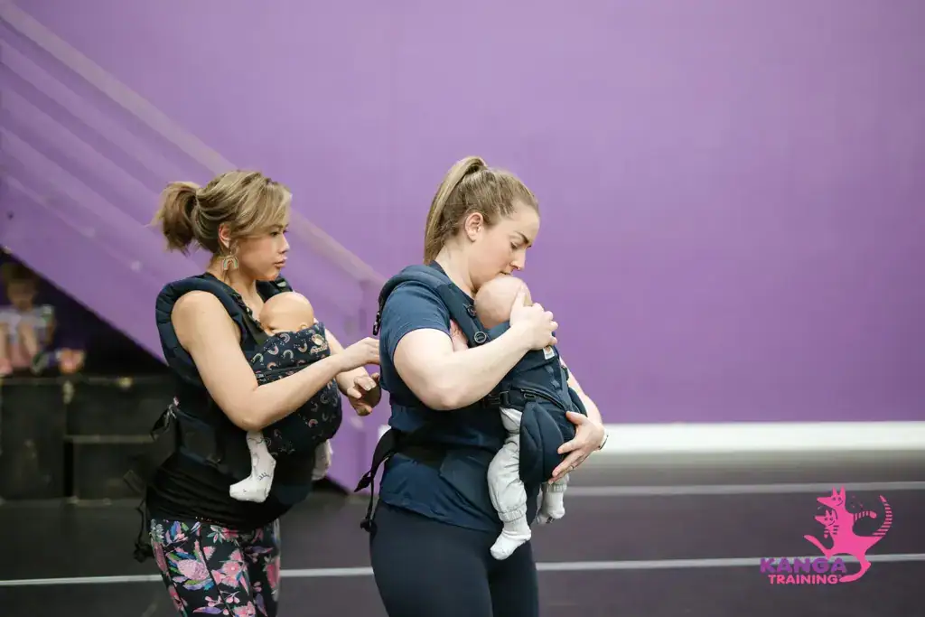 Trainer helping mum with their baby carrier