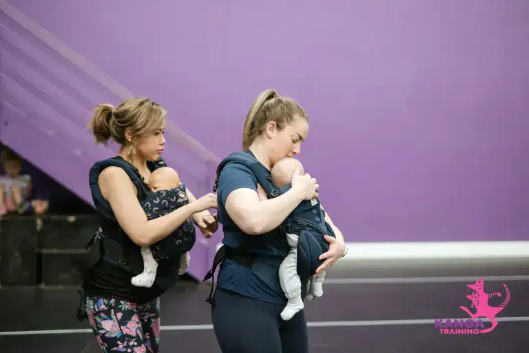 Trainer helping mum with their baby carrier